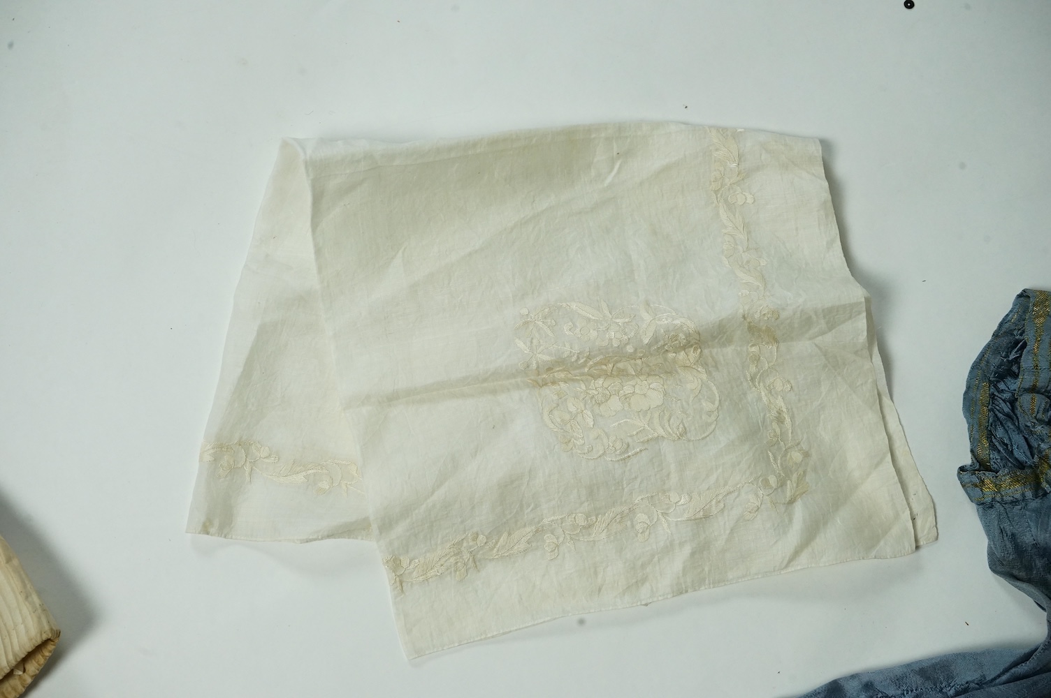 An early 19th century cream silk and metal thread embroidered ladies bonnet, an interesting 1930’s blue silk and gold thread dress fabric designed with Secessionist influences, an earlier fine linen silk embroidered kerc